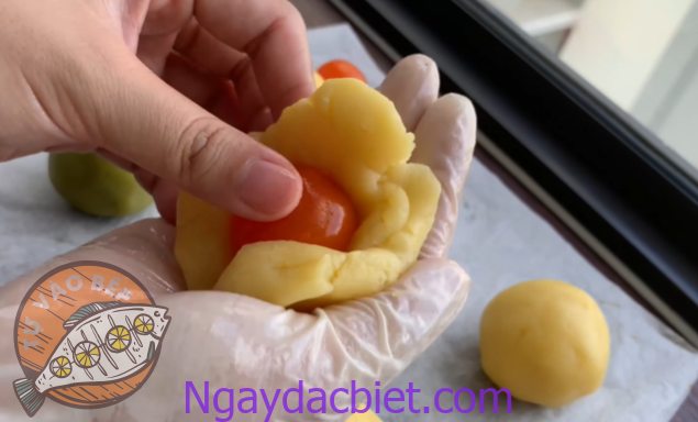 Cho trứng muối vào giữa và miết kín phần đậu xanh, tạo vỏ bao quanh nhân trứng